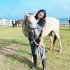 A Vet student wearing cool gray scrubs with gumboots and looking after a horse